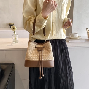 Détail du sac seau en paille tressée avec base en cuir et fermeture à cordon
