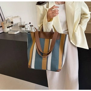 Detail of striped canvas tote bag with brown leather handles and spacious interior