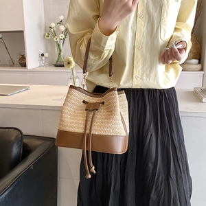 Détail du sac seau en paille tressée avec base en cuir et cordon de serrage en intérieur