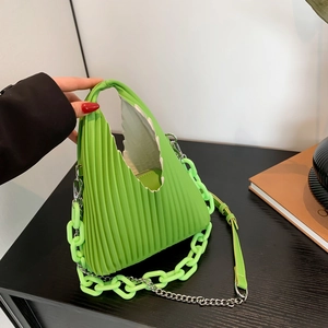 Detail of bright green pleated PU leather bag with sawtooth edge and plastic chain link
