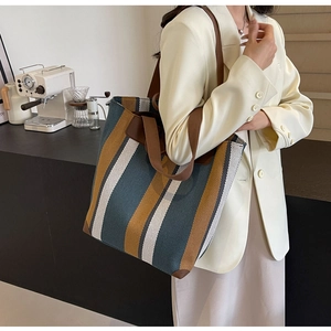 Detail of striped canvas tote bag showing side capacity and brown leather trim accents