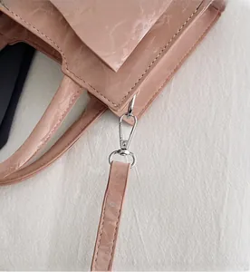Close-up of polished silver metal hooks and pink synthetic leather on a small handbag