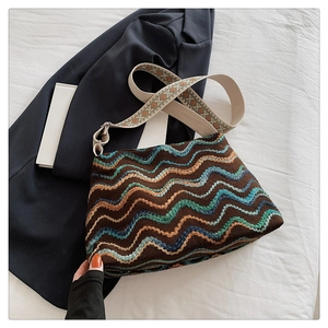 Détail d'un sac seau bohème en tricot avec motifs de vagues colorées et large bandoulière jacquard