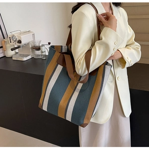 Detailed view of striped canvas tote bag with brown leather handles and reinforced base