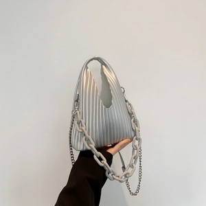 Detail of silver pleated PU handbag with dual metallic chains and integrated handle design