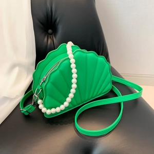 Detail of green shell shaped PU bag featuring large pearl handle and silver metal zipper