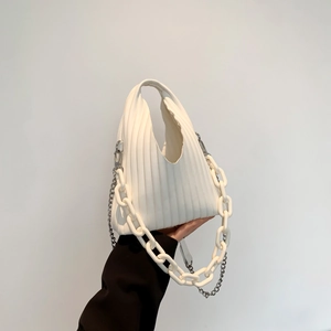 Detailed shot of white pleated handbag featuring a thick plastic chain and metal strap