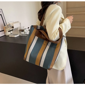 Detailed close-up of large canvas tote bag with navy and yellow stripes and leather handles