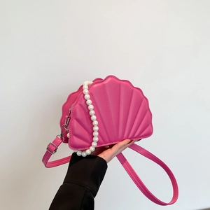 Detail of shell-shaped crossbody bag featuring large pearl handle and pink PU leather