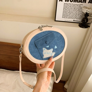 Detailed close-up of blue denim crossbody bag with cute cat embroidery and chain strap