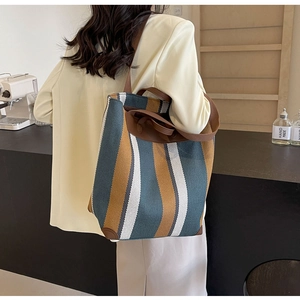 Model showcasing a large canvas tote bag with blue, orange, and white vertical stripes