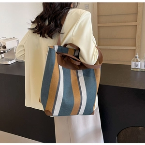 Detail showing high-capacity striped canvas tote with reinforced brown leather handles and corners