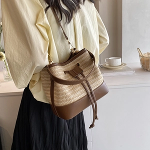 Vue détaillée du sac seau bicolore en paille avec cordon en cuir et texture tissée chic