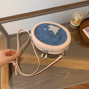 Detail of a pink leather and blue denim crossbody bag with cute animal patches and heart motif