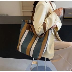 Detail of striped canvas tote bag with brown leather trim and sturdy shoulder strap