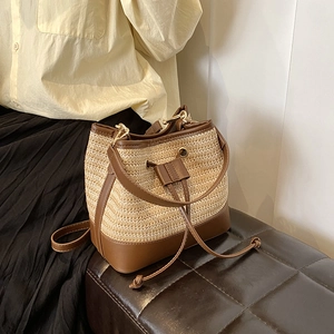 Détail du sac seau en paille avec cordon, bordures en cuir marron et finitions dorées