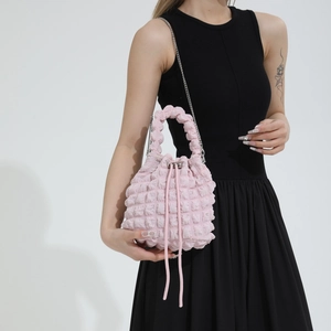 Close-up of pink pleated bubble texture bucket bag with silver chain strap on model
