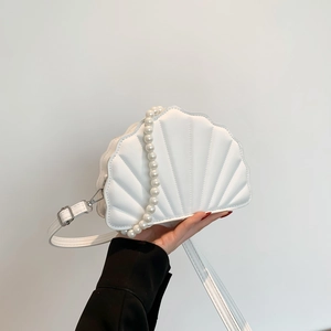 Detail view of a white shell-shaped PU bag with large imitation pearl handle and quilted texture