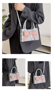 Close-up of silver pleated crossbody bag featuring a large pink bow and heart buckle