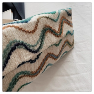 Détail de sac seau bohème en laine avec broderie à vagues multicolores texturées