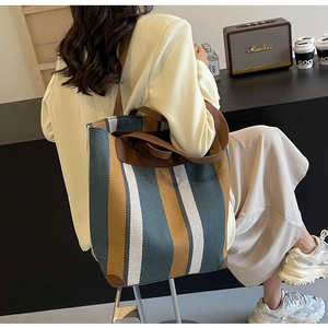 Chic striped canvas tote bag with brown leather straps styled in a modern urban setting