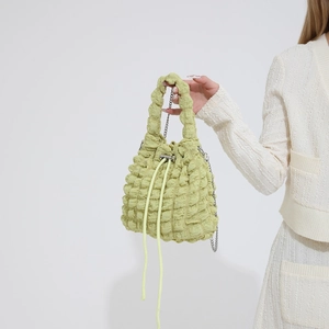 Detailed view of light green popcorn textured bag with silver chain and drawstring