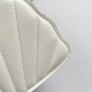Detailed macro view of white quilted faux leather bag with elegant V-shaped stitching