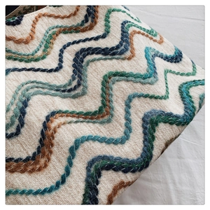 Gros plan du sac seau bohème avec broderie vagues colorées et tissu texturé de qualité
