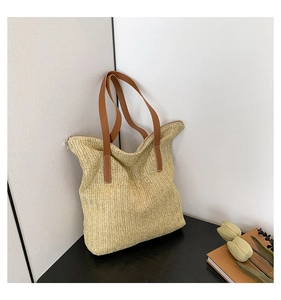 Détail d'un sac cabas en paille tressée avec bandoulière en cuir et fermeture éclair