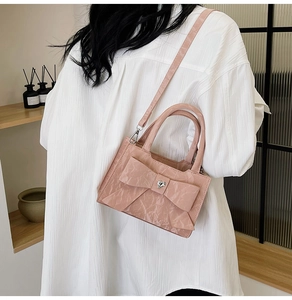 Detail of pink glossy leather handbag featuring large bow and heart-shaped silver ornament
