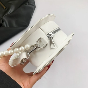 Detail of white flower shell bag featuring pearl bead handle and silver metal zipper