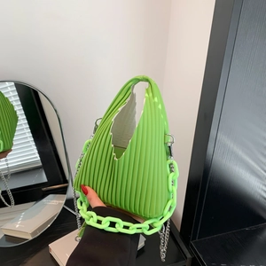 Detail of bright green pleated PU handbag with chunky acrylic and metal chain straps