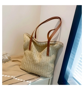 Détail du sac cabas en paille avec bandoulières en similicuir brun et texture tressée fine