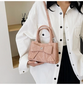 Pink crossbody bag detail showing heart-shaped crystal buckle on faux leather texture