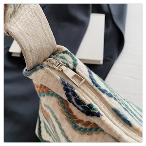Détail du sac seau en laine bohème avec fermeture éclair argentée et bandoulière