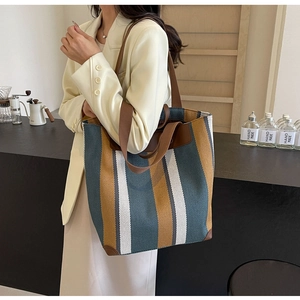 Close-up of contrast striped canvas tote bag showing reinforced leather corners and handles