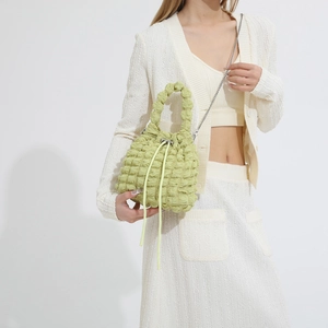 Detail view of light green bubble texture drawstring bucket bag on a fashion model
