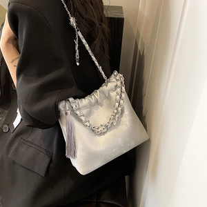 Detailansicht der silbernen Metall-Eimertasche mit Cracker-Struktur und Quaste am Modell