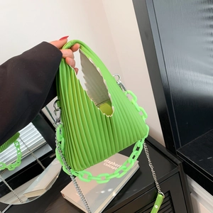 Macro detail of grass green pleated leather bag with stylish acrylic and silver chains