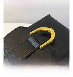 Detailed macro view of black leather texture and premium gold D-ring hardware finish