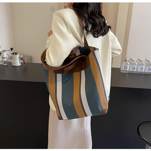 Detail of the striped canvas tote bag showing reinforced leather corners and handles