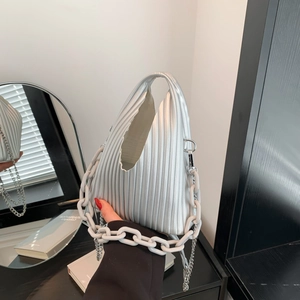 Macro shot of silver pleated PU handbag texture with metallic chain and white link strap