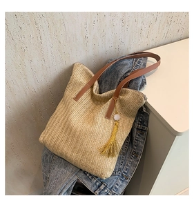 Détail du sac en paille avec texture tissée diagonale et poignée en similicuir marron