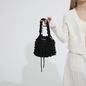 Detailed view of the black popcorn texture bucket bag with chain strap on a model