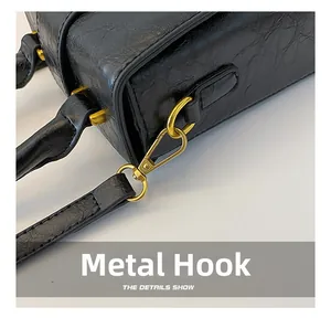Close-up of golden hardware clasp on black leather bag with vintage pleated texture
