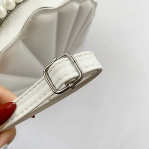 Detail of white shell purse with faux pearl ring handle and adjustable silver buckle strap