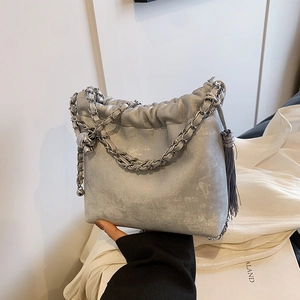 Detail der grauen Plisse-Beuteltasche mit silberner Kette und Quastenanhänger
