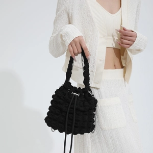 Close-up of black popcorn textured cloud bag with woven handle and silver chain strap