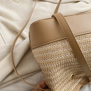 Détail du sac seau en paille tressée et cuir avec œillets métalliques dorés fins