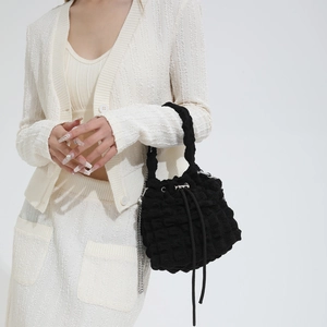 Detail shot of black bubble textured cloud bucket bag with chain strap and drawstring